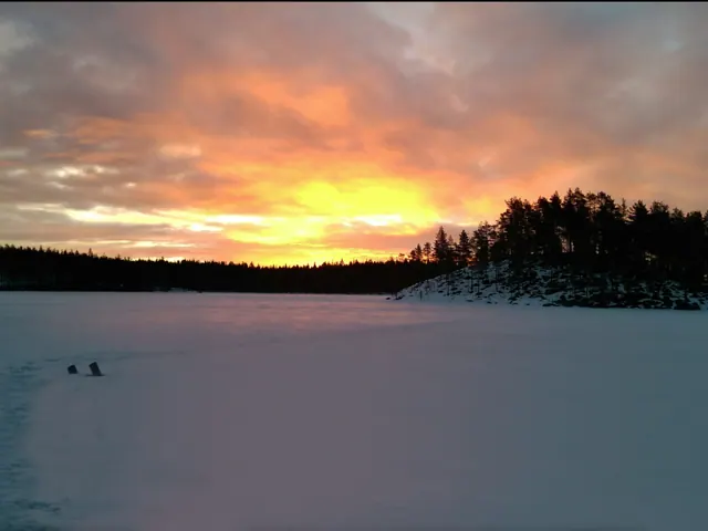 Soluppgång över den snötäckta sjön